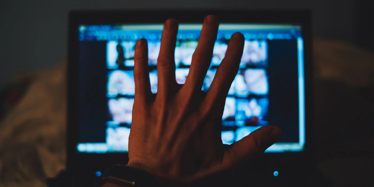 Hand op scherm terwijl iemand worstelt met pornoverslaving en online verleiding