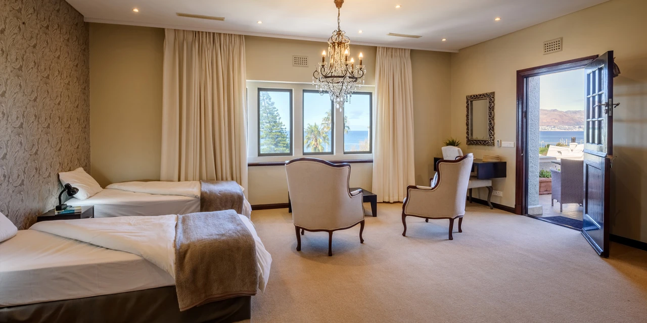 Spacious double room with two beds, armchairs and a sea view.