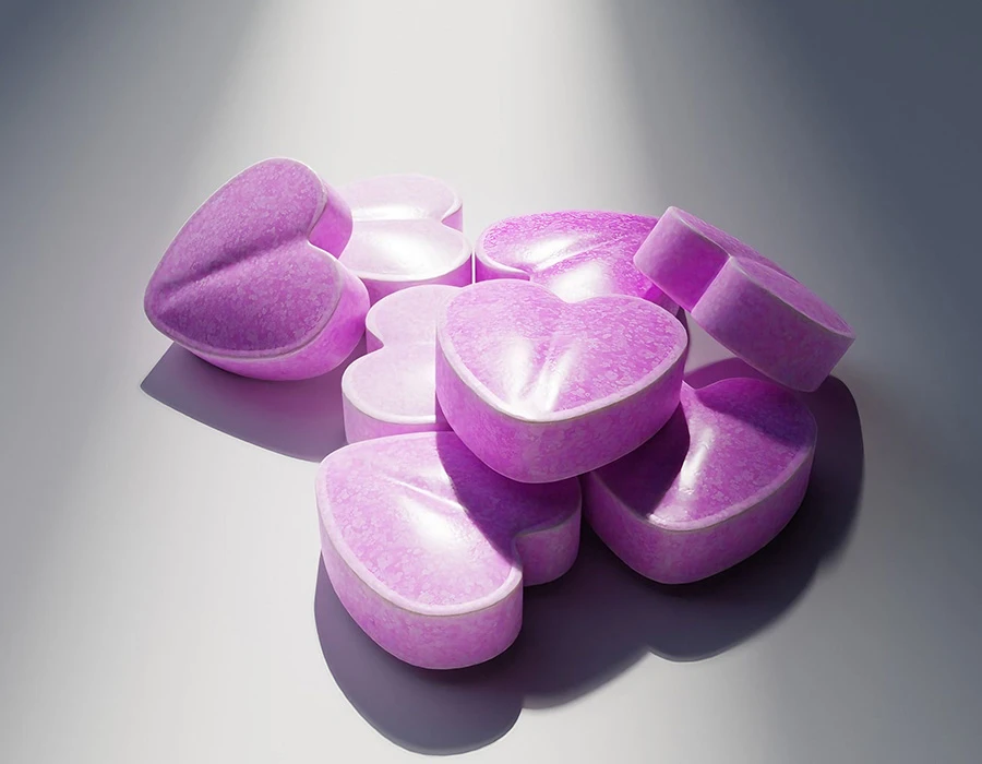 Roze XTC-pillen in verschillende vormen op een lichte ondergrond.