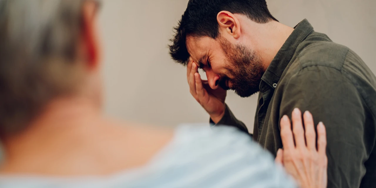 Man met stress en steun van ander persoon tijdens herstel van speedverslaving.