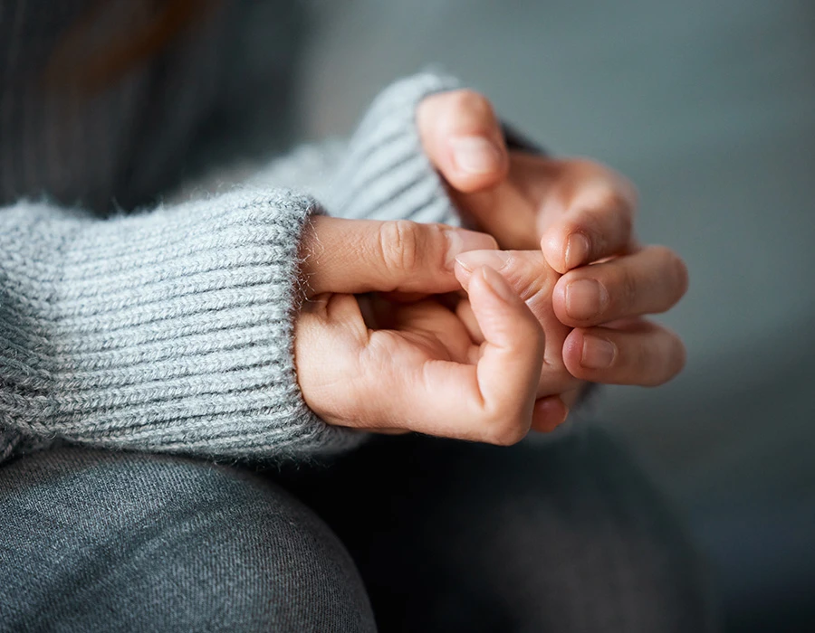 Handen die zenuwachtig friemelen, symbool voor innerlijke onrust en trauma.