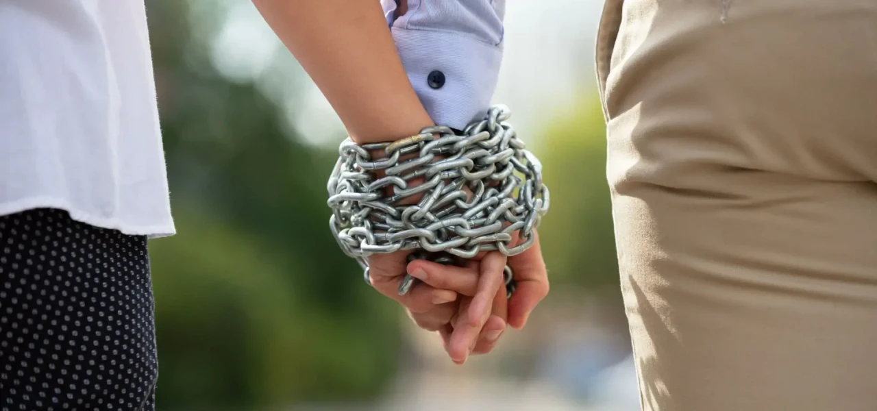 handen-vastgebonden-ketting De handen van twee lopende personen zijn aan elkaar vastgebonden door een ijzeren ketting.