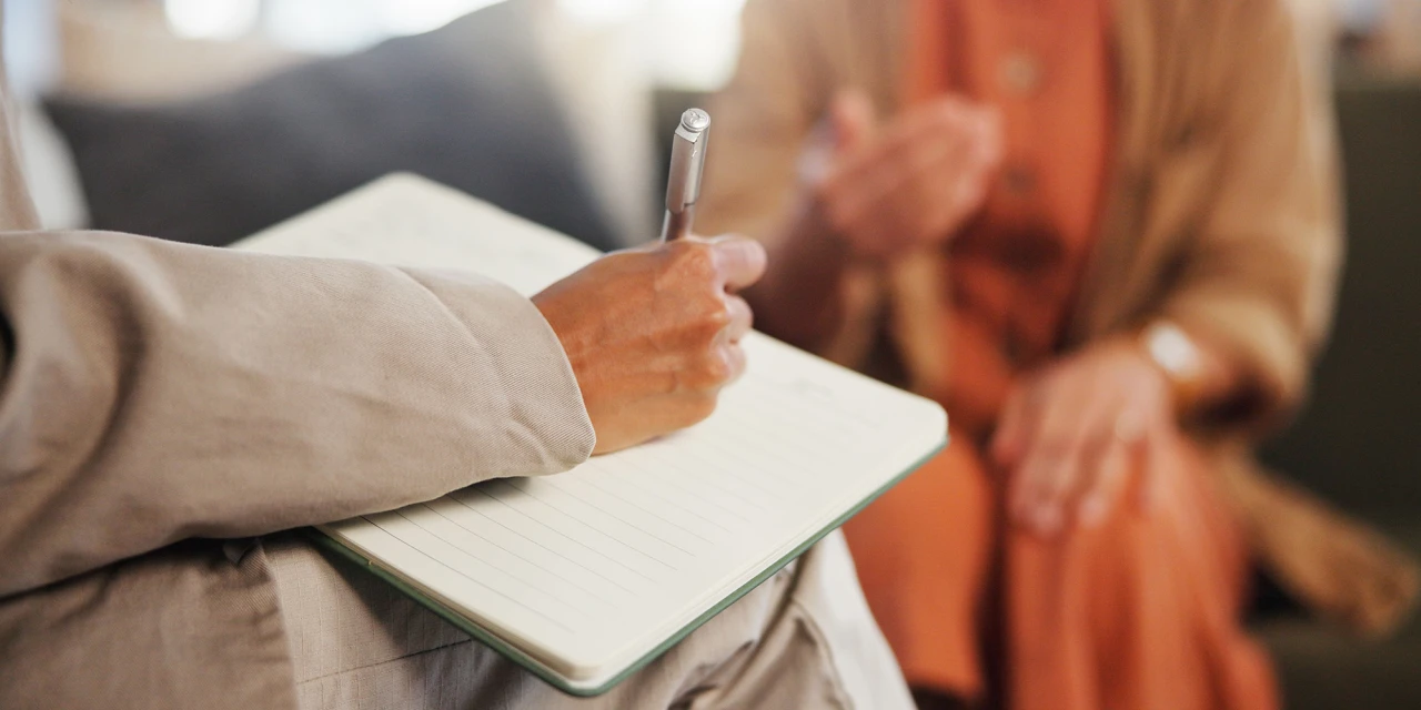 Psycholoog maakt aantekeningen tijdens gesprek met cliënt.