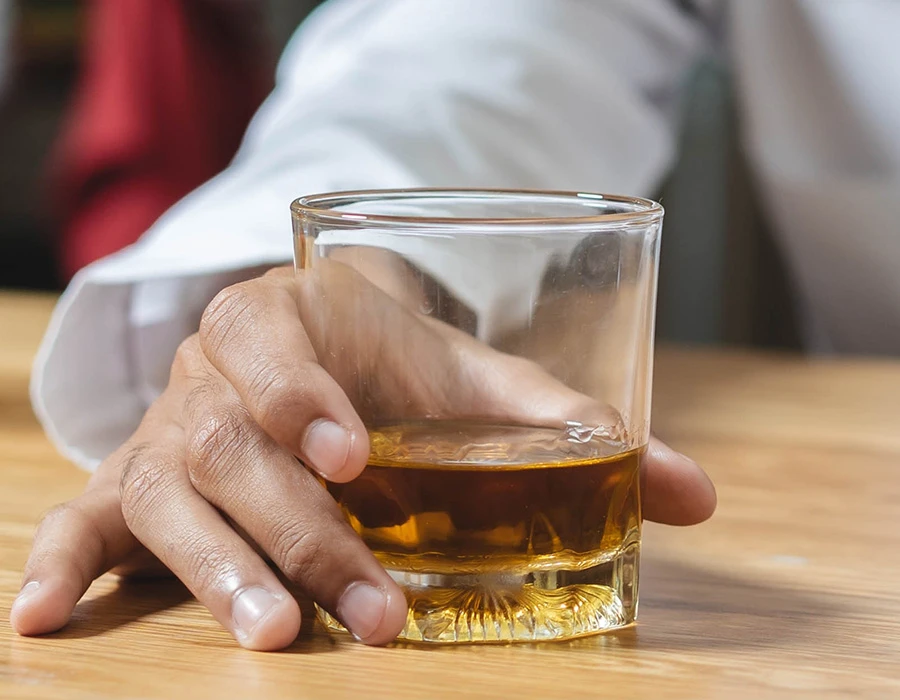 Man heeft whiskey in zijn hand en heeft last van een alcoholverslaving.