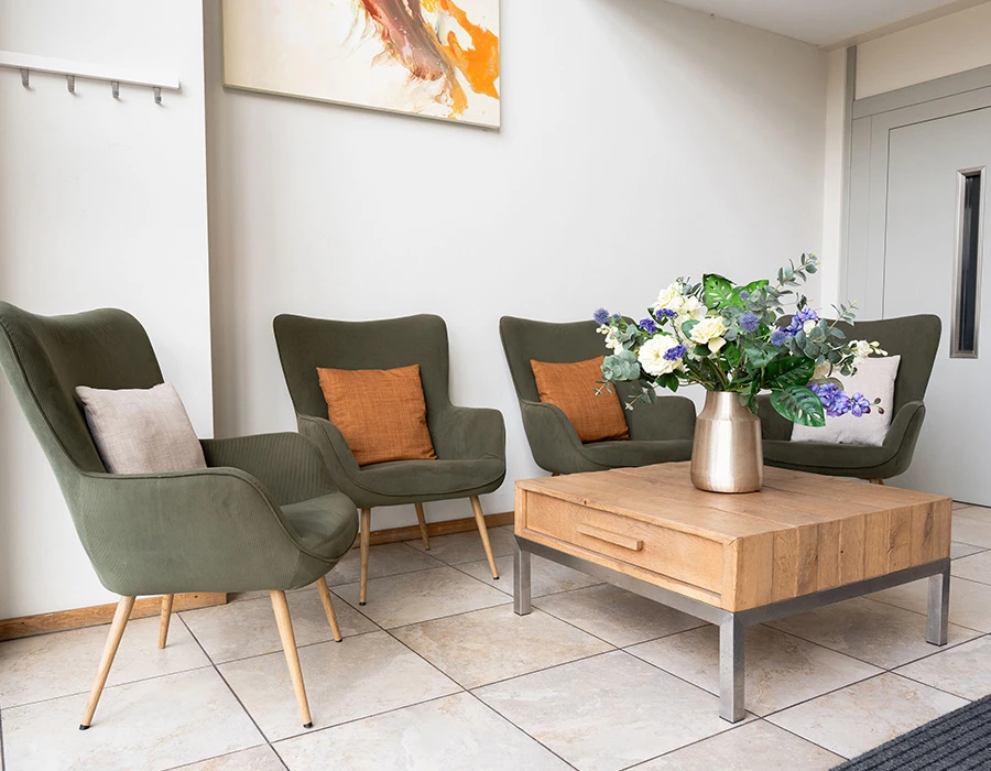 Hal van afkickkliniek Meerlo met fauteuils en houten tafel.