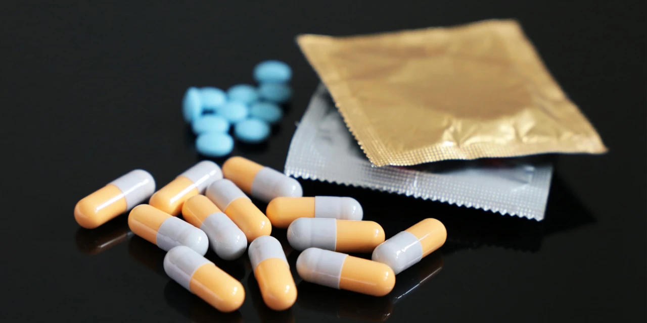 Capsules en condooms op tafel, verbonden met het gebruik van drugs tijdens chemsex.