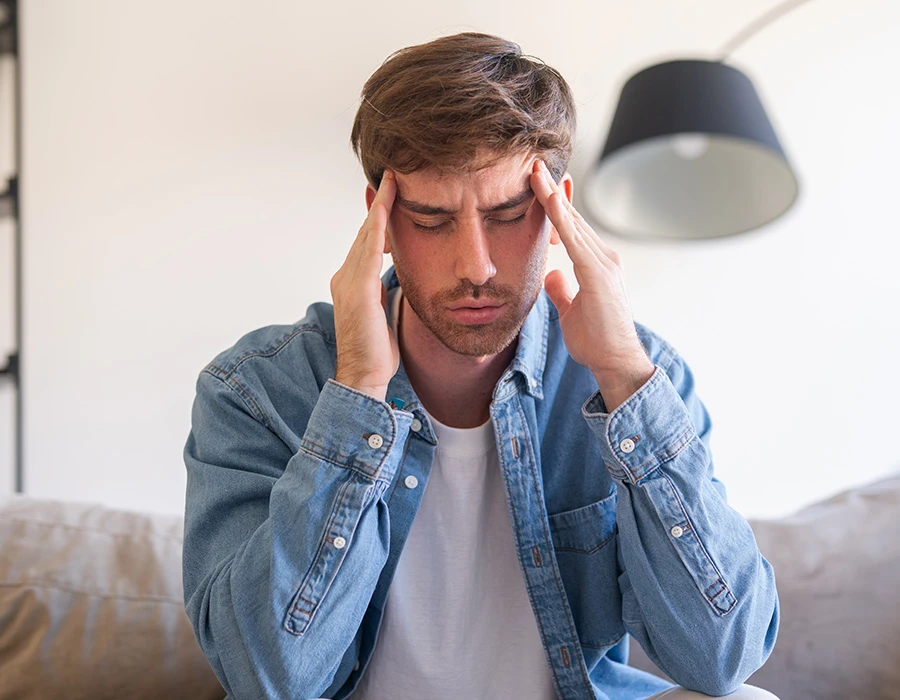 Man met zijn vingers tegen zijn slapen, ter illustratie van cannabishyperemesissyndroom.