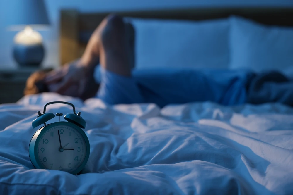 Wekker op drie uur ‘s nachts met iemand wakker in bed, ter illustratie van plafonddienst.