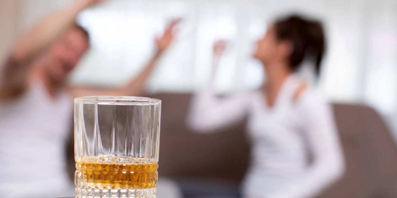 Glas op tafel bij ruzie toont alcohol en relatieproblemen in huiselijke sfeer.