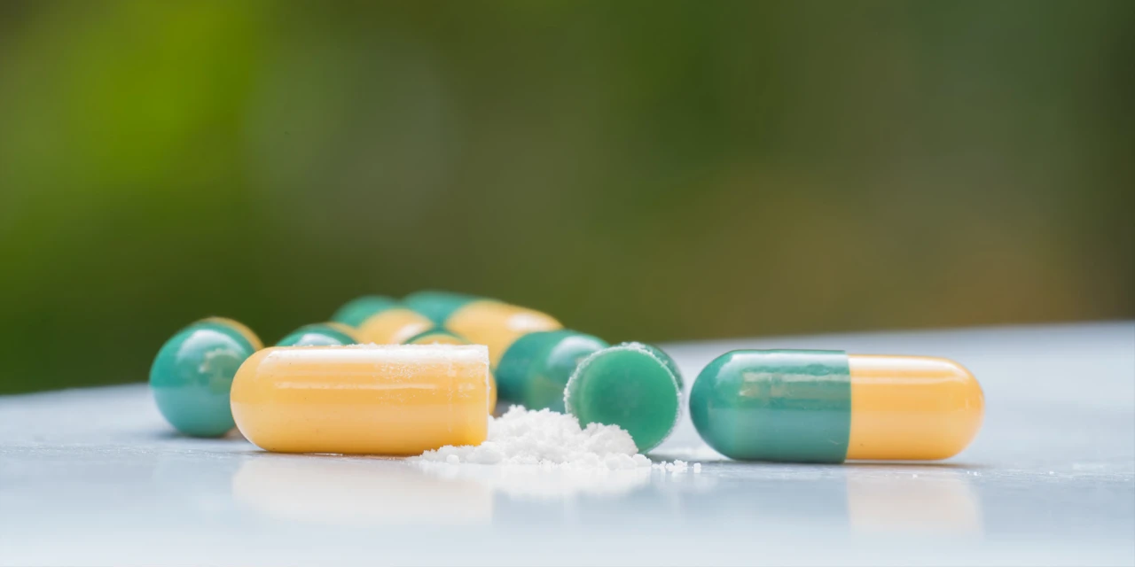 Groene en gele capsule met poeder ernaast.