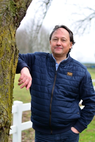 Gavin, teamlid van Connection SGGZ, leunt ontspannen tegen een boom.