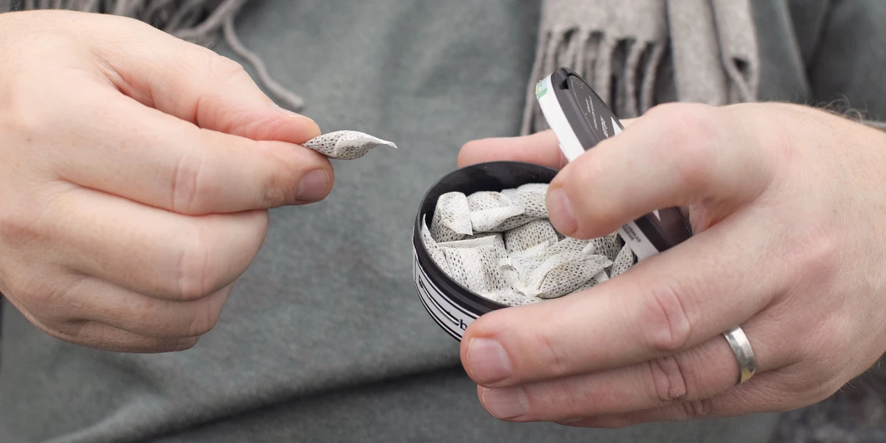 Hand met snus zakjes uit verpakking.