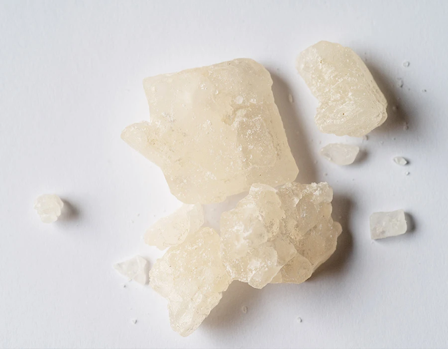 Witte kristallen van MDMA op een lichte ondergrond.