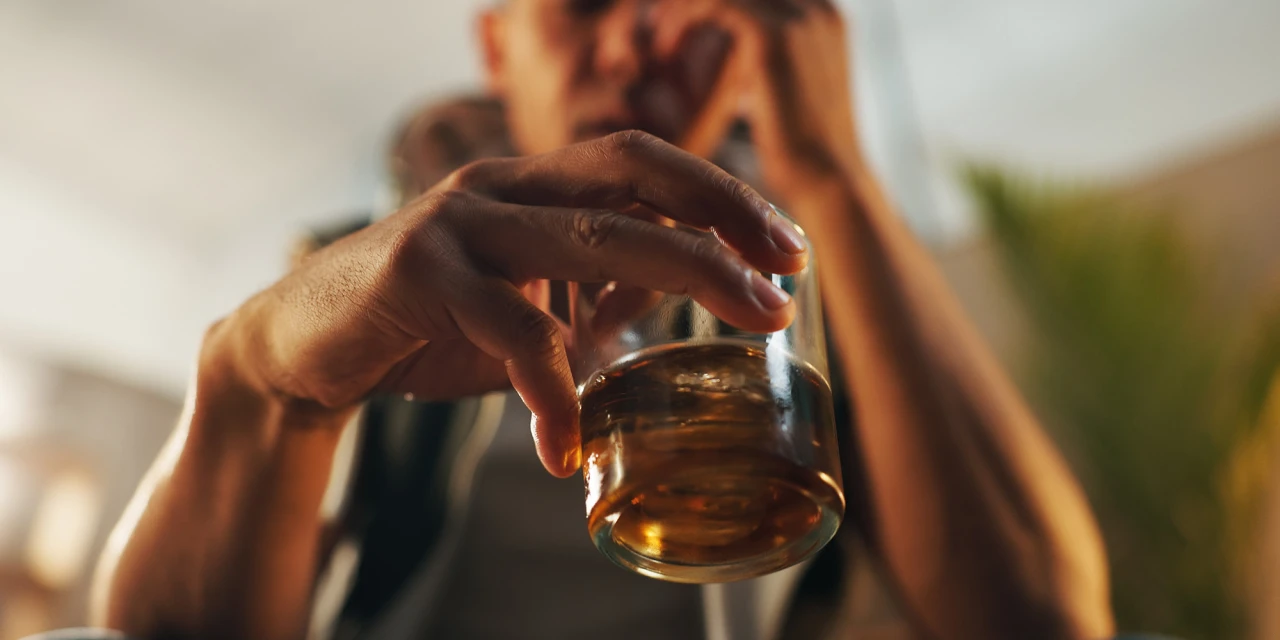 Man houdt glas vast en is alcohol drugs aan het gebruiken.