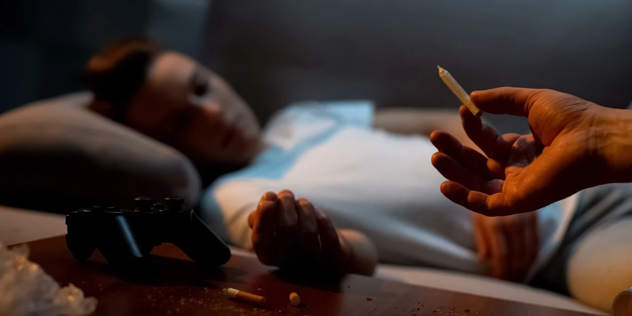 Persoon ligt versuft met joint in hand. Invloed van blowen op emoties en depressie zichtbaar.