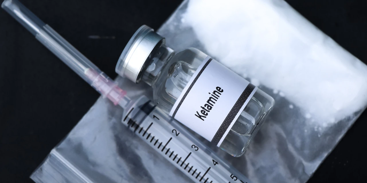 Flesje ketamine met spuit en poeder die de effecten ketamine weerspiegelen.