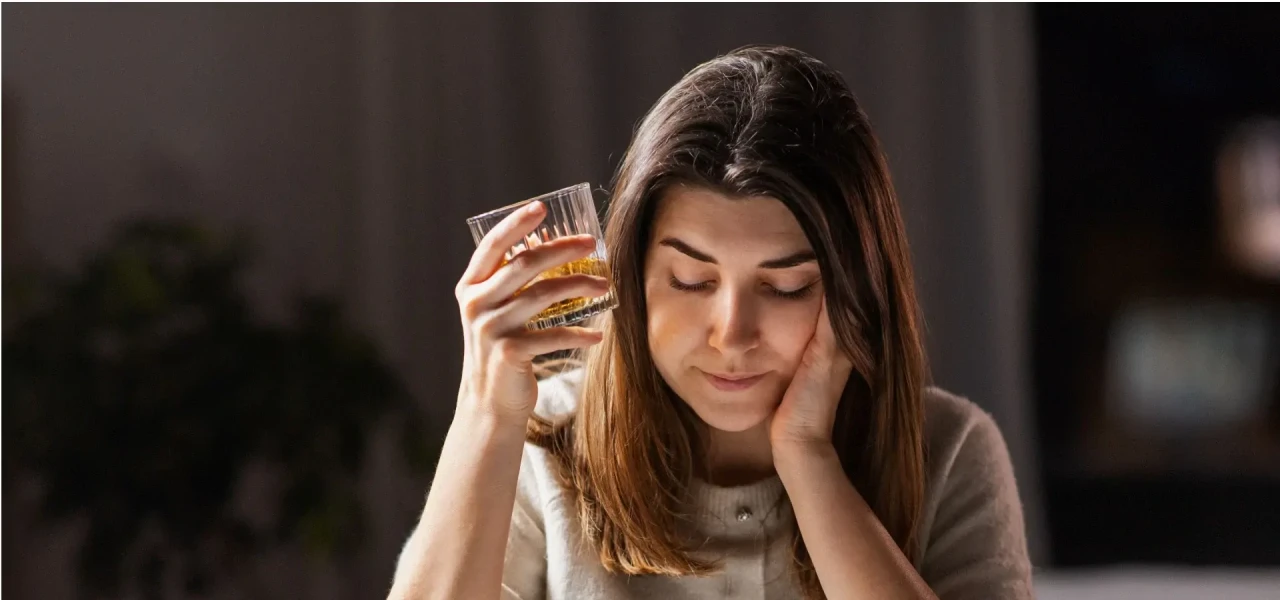 vrouw-met-alcoholverslaving Vrouw met alcoholverslaving heeft een glas drank in haar hand en kijkt naar beneden.