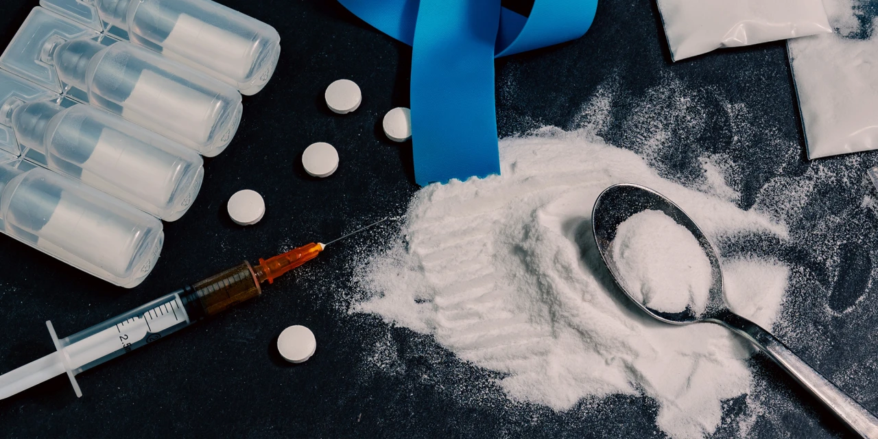 Een spuit en drugs liggen klaar terwijl iemand zich afvraagt wat een overdosis is.