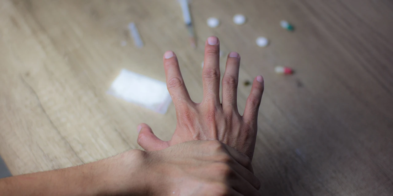 Hand duwt andere hand weg van tafel met kenmerken verslaving duidelijk zichtbaar.