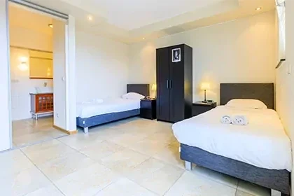 meerlo-slaapkamer Slaapkamer met witte muren, twee bedden en een kast tussen de bedden.