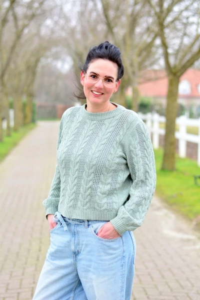 Ellen, teamlid van Connection SGGZ, staat met haar handen in haar zakken voor een oprit.
