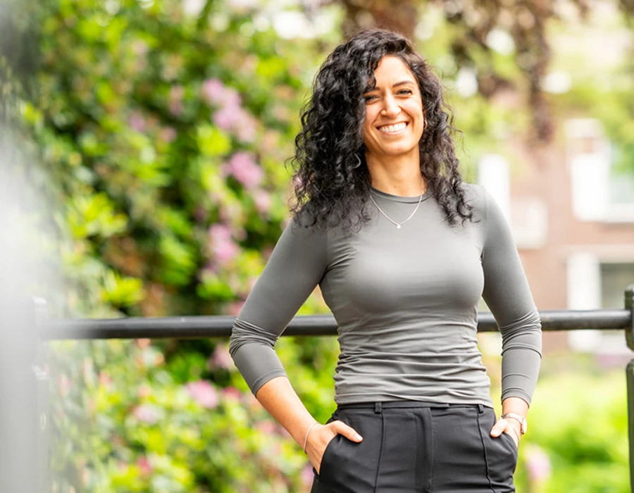 Mirjam, lid van het team van Connection SGGZ, staat vriendelijk lachend voor een hek.