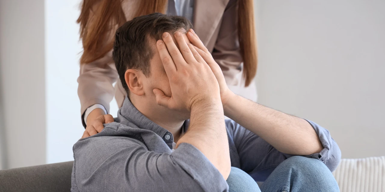 Man met handen voor gezicht krijgt steun van ander persoon.