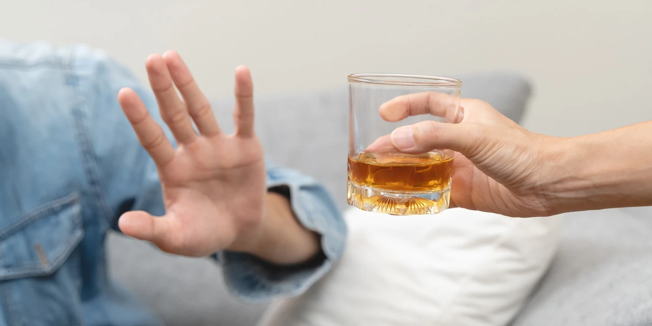 Hand wijst glas whisky af als teken van stoppen met alcohol.