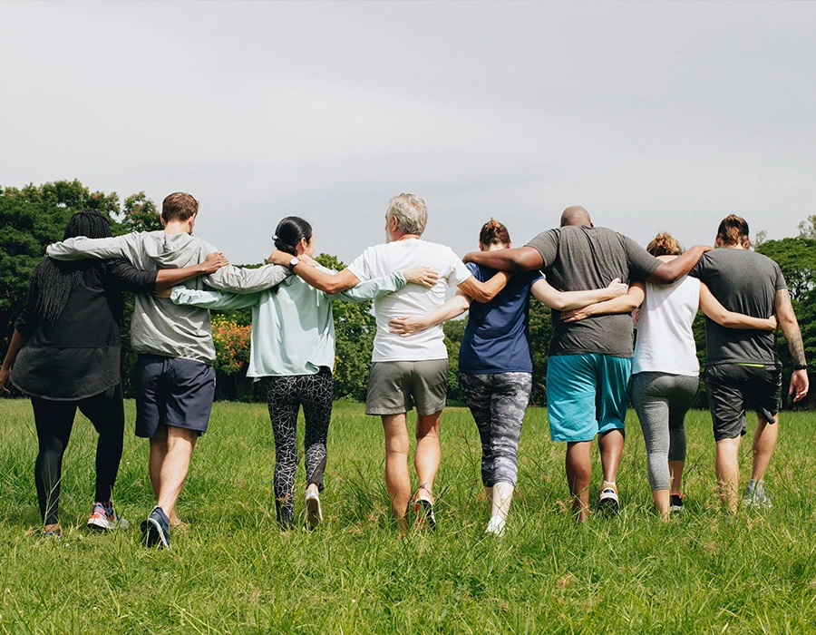Groep mensen loopt arm in arm in natuur, symbool voor verbinding bij autisme.