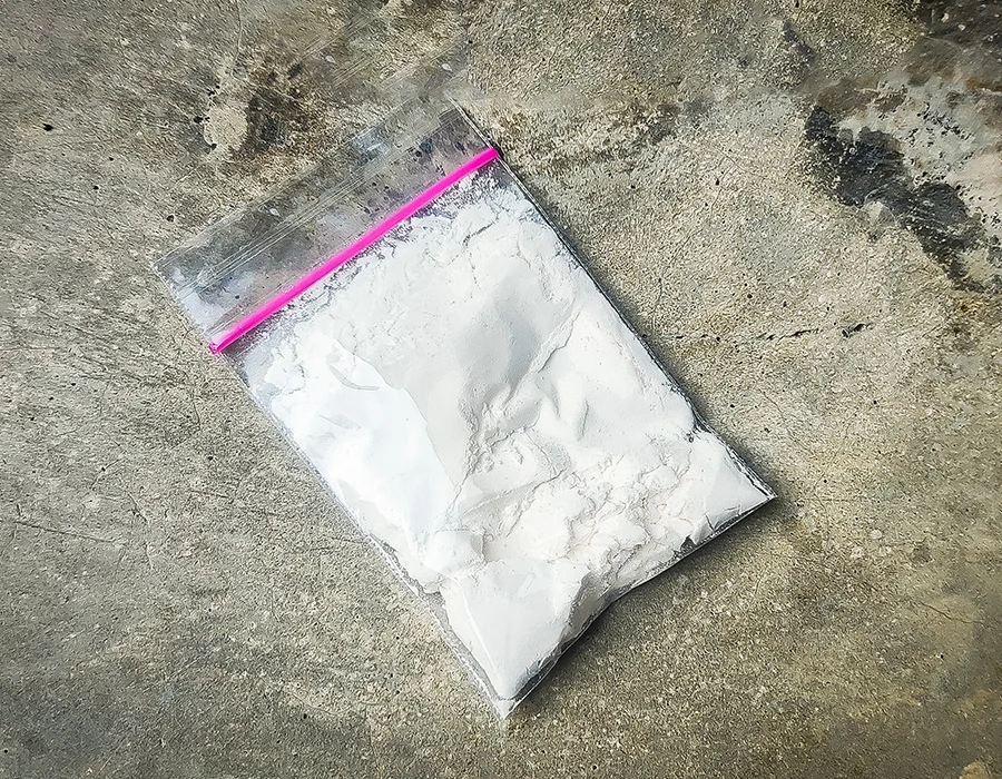 Zakje met wit poeder op een betonnen vloer, ter illustratie van de designerdrug 2-MMC