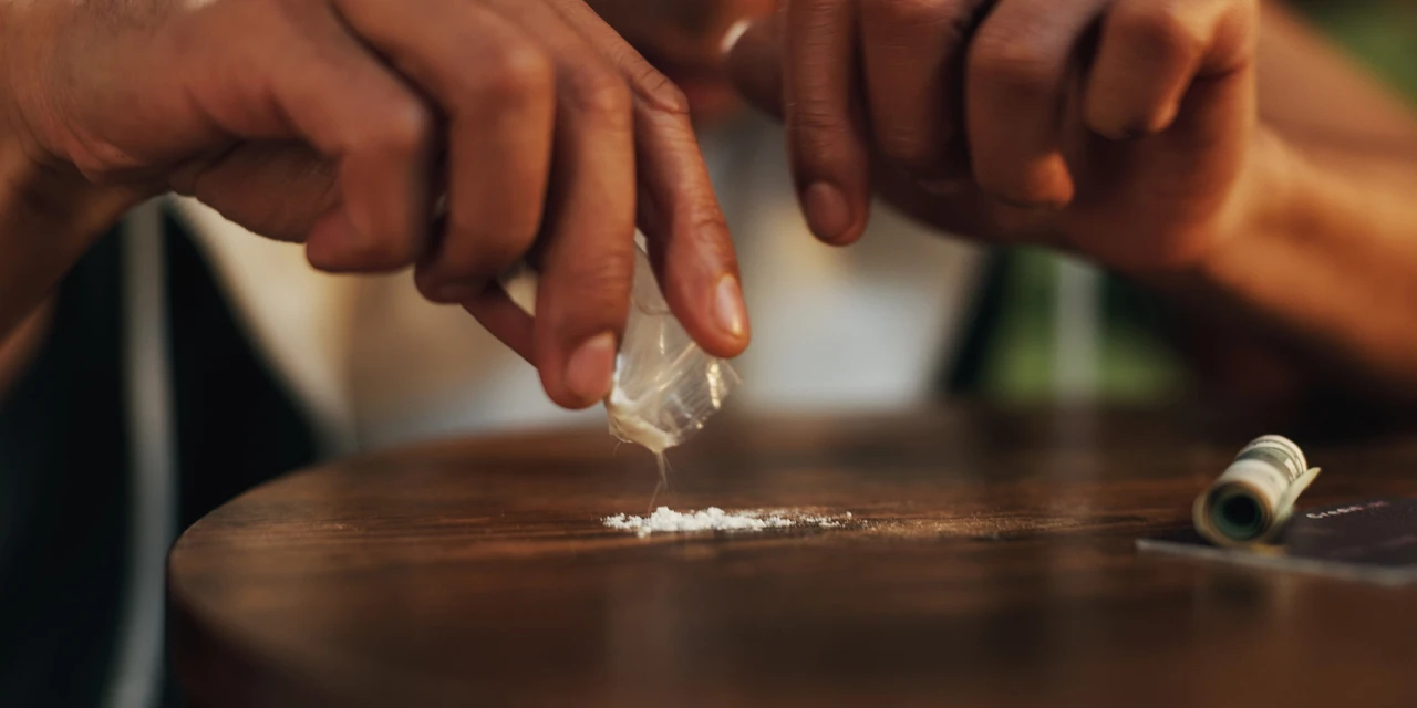 Hand strooit poeder op tafel en denkt aan stoppen met drugs.