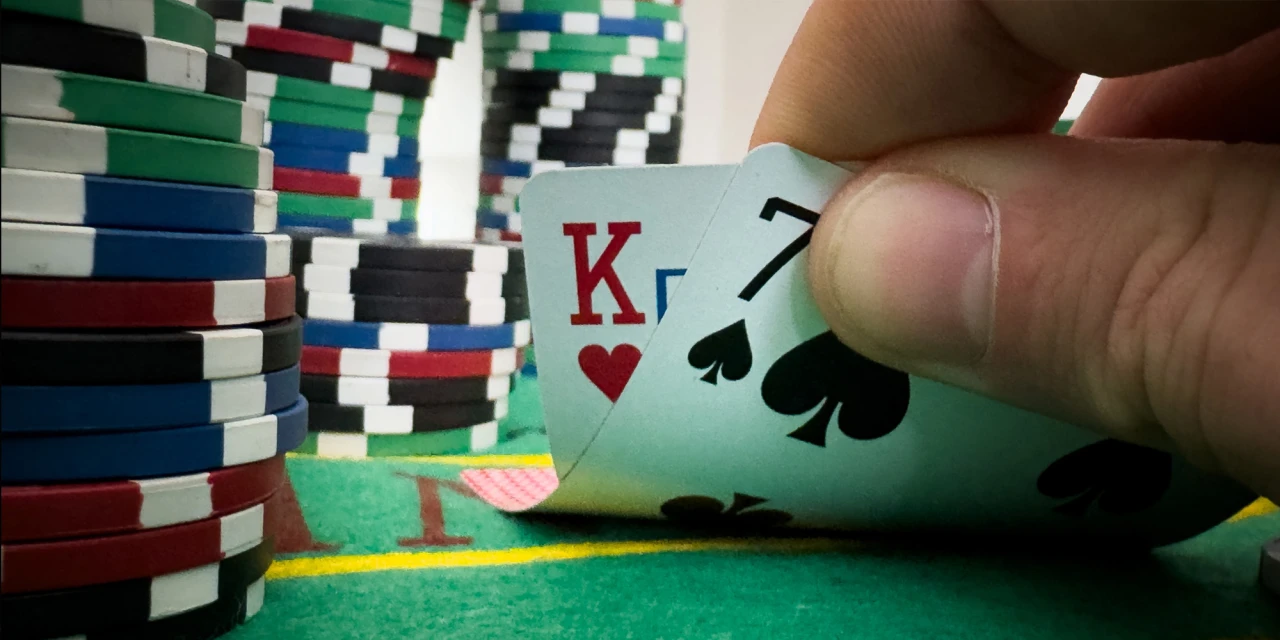 Een speler met een hand kaarten en fiches door zijn pokerverslaving.