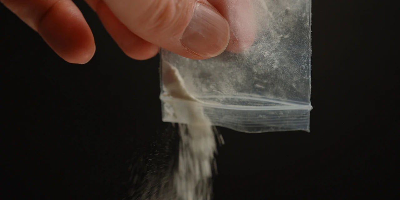 Hand giet wit poeder uit zakje mogelijke drugs voor een k-hole.