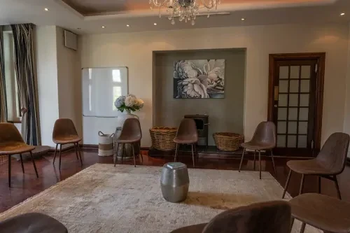zuid-afrika-behandelkamer-kringgesprek Behandelkamer met bruine leren stoelen in een kringopstelling rondom een beige vloerkleed.