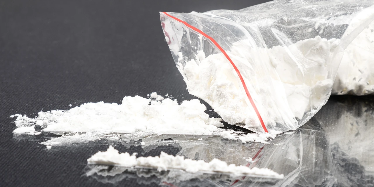 Zakje met wit amfetaminepoeder en lijnen op tafel.