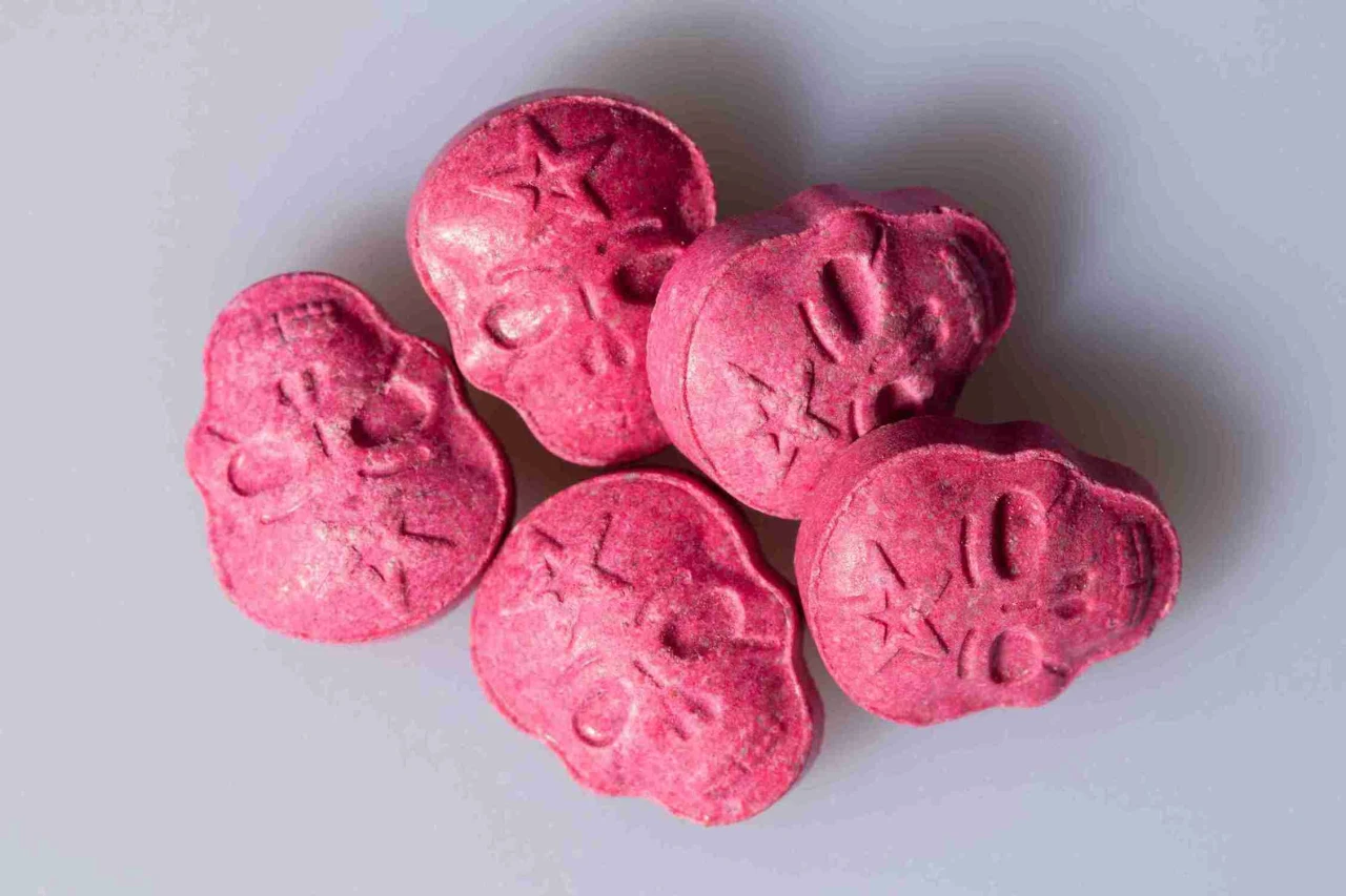 Roze pilletjes in de vorm van doodskopjes die laten zien wat XTC is en hoe deze drug eruit kan zien.
