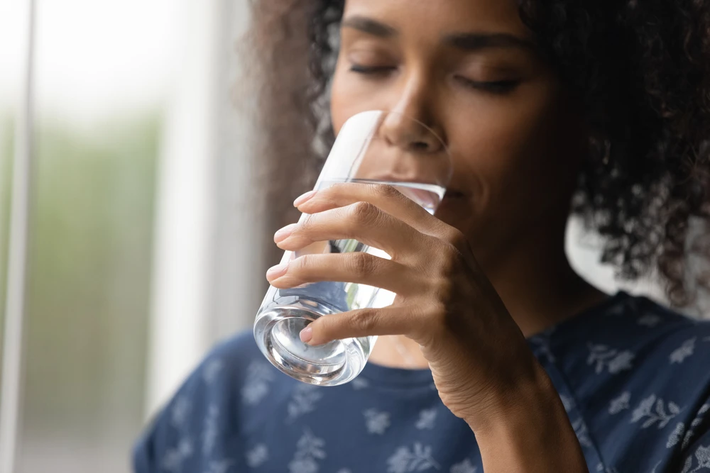 Vrouw drinkt water als onderdeel van haar detoxproces in een ondersteunende omgeving.