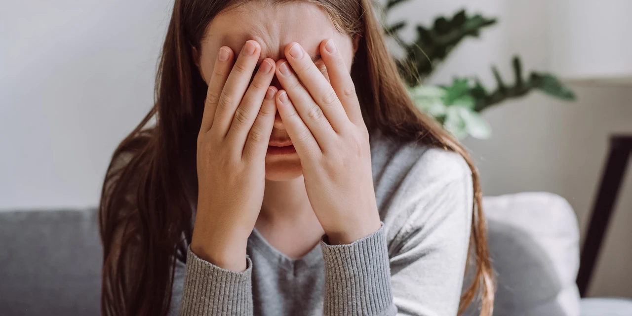 Meisje met handen voor gezicht ervaart afkickverschijnselen wiet.