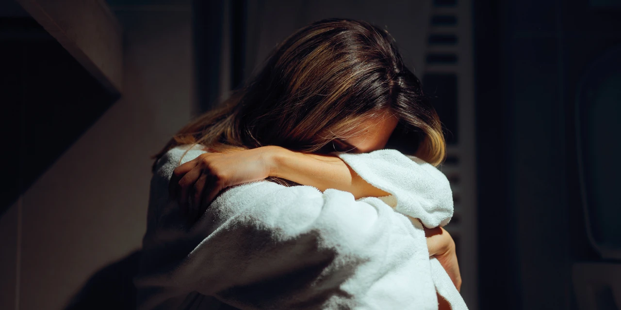 Vrouw in badkamer zit uitgeput op de grond met morfine als pijnbestrijding.