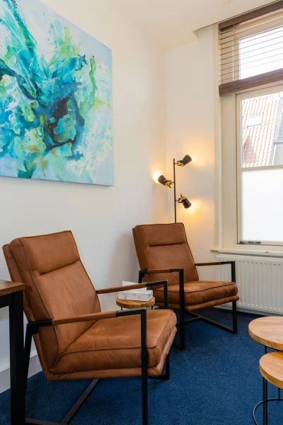 Ruimte voor een familiebijeenkomst, met comfortabele stoelen en kunstwerk.