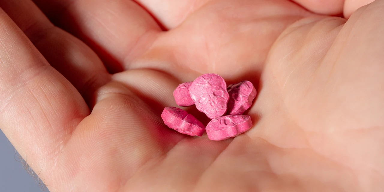 Hand met roze pillen in de handpalm.