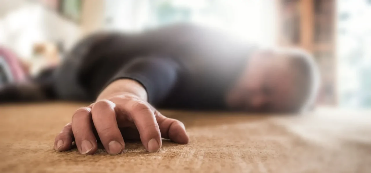 Bewusteloze man, liggend op de grond, door alcoholvergiftiging, met de hand in focus en het hoofd wazig.