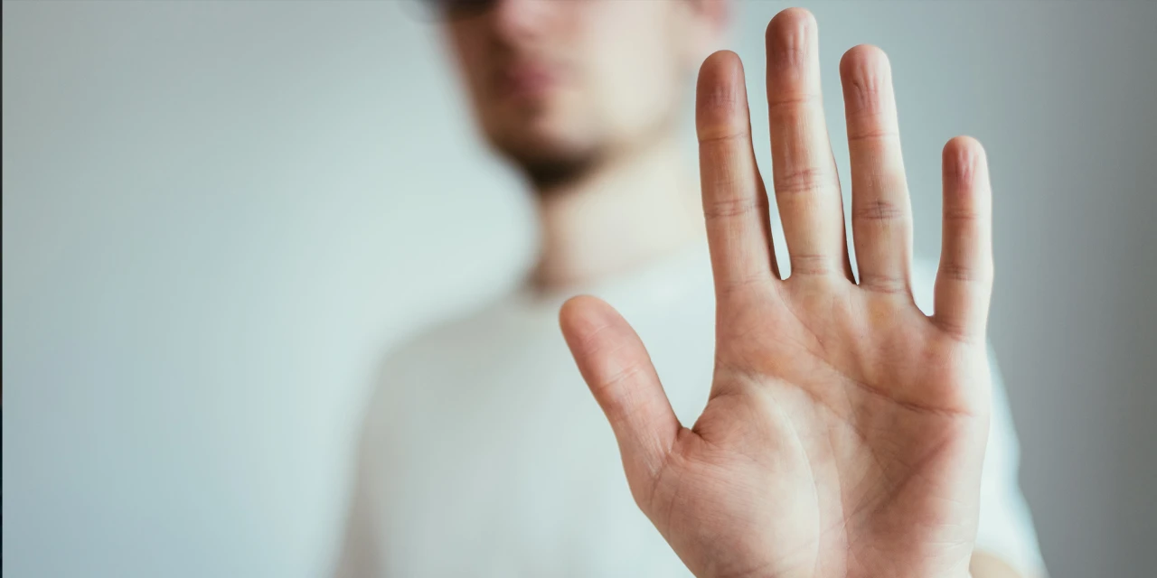 Man steekt hand naar voren als stopteken en probeert grenzen te stellen tegen verslaving en onderliggende problematiek.