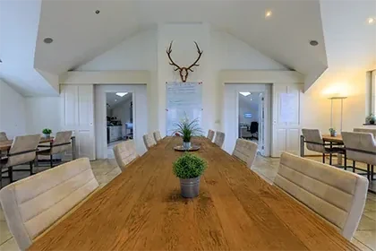 meerlo-vergaderruimte Vergaderruimte met lange houten tafel, beige stoelen en een gewei aan de muur tussen twee deuren in.