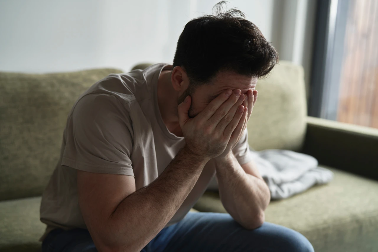 Last-van-afkickverschijnselen-gokken Man verbergt gezicht in handen omdat hij last heeft van de afkickverschijnselen van gokken.