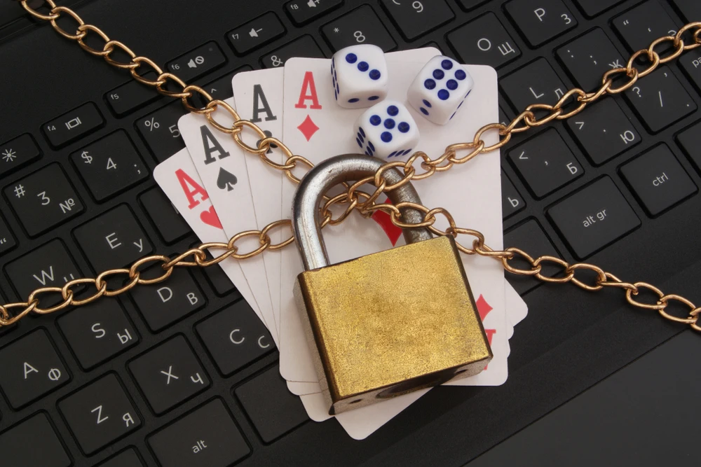 Speelkaarten, dobbelstenen en een toetsenbord met een ketting en hangslot – symbool voor stoppen met gokken en controle terugkrijgen.
