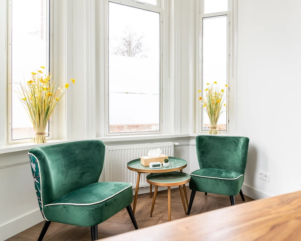Afkickkliniek Eindhoven hoofdkantoor zithoek met groene stoelen.