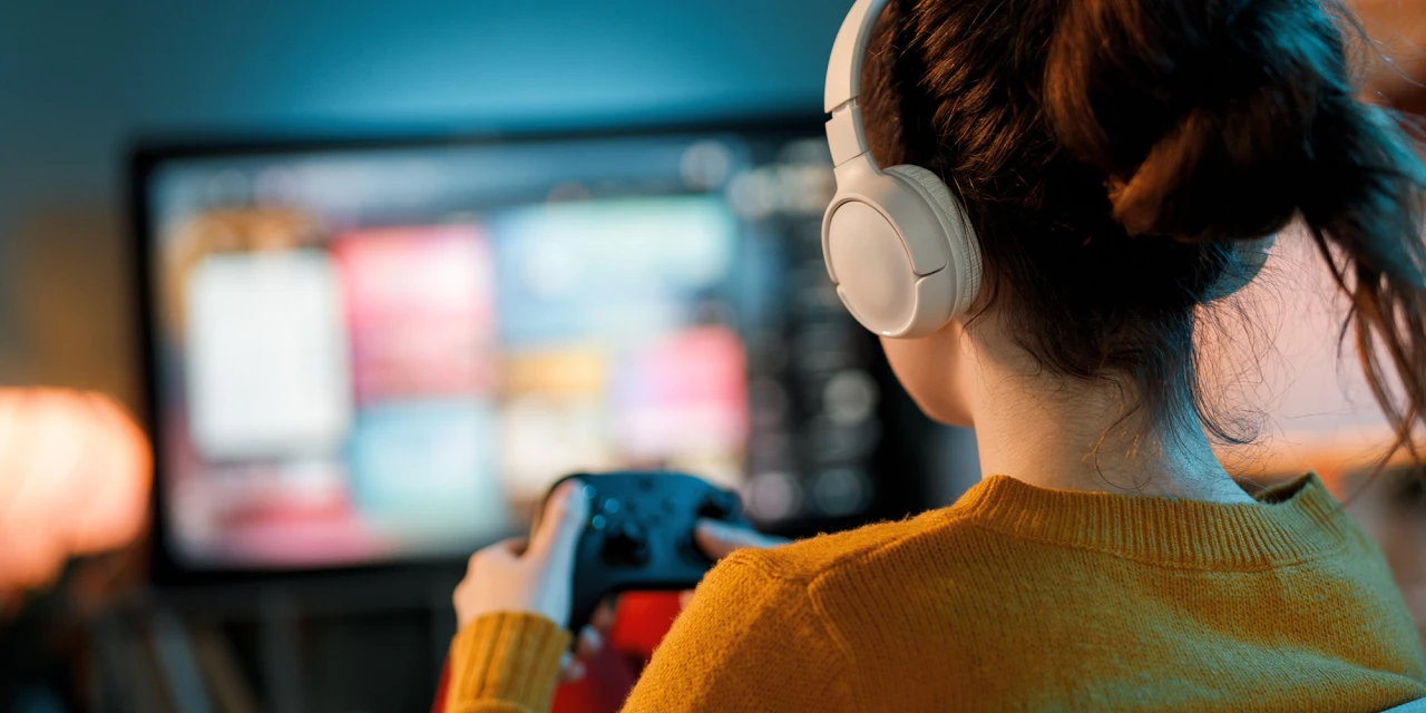 Vrouw speelt geconcentreerd videogame met koptelefoon mogelijk teken van gameverslaving.