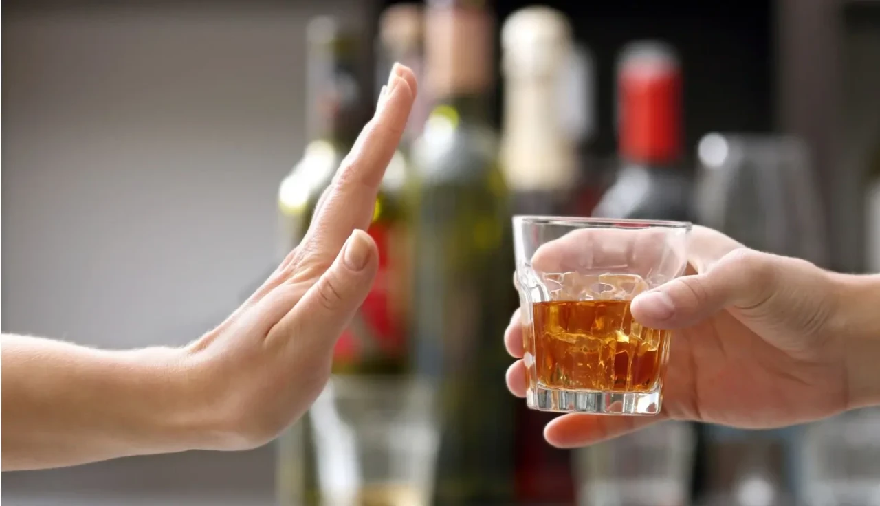Een hand met een wiskeyglas tegenover een hand die het signaal geeft om te stoppen met drinken. 