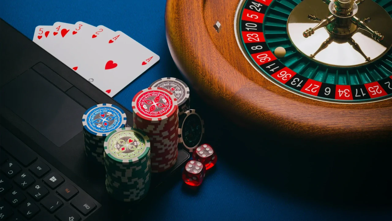 Blauwe tafel met gokattributen zoals fiches, kaarten, toetsenbord en roulettewiel.